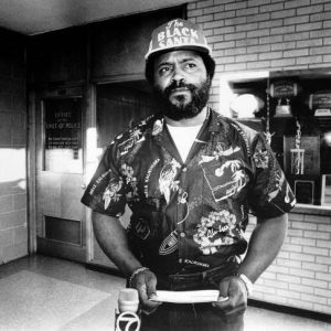 Interior police station black man wearing "the black santa" hat holding paper news microphone foreground