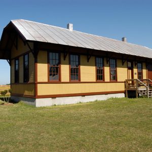 rectangular yellow wooden building with stairs leading to entrance