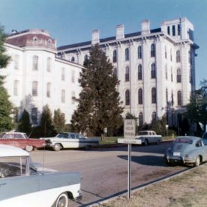 Multistory buildings on parking lot with trees and parked cars