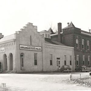 Long two-story building with single story addition with "Arkansas State Police" signs and arched entrance ways