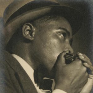 African-American man in suit and hat playing a harmonica