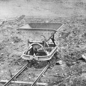 men in hats boots and pants with suspenders loading a mine cart with shovels