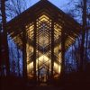 Lighted glass-walled chapel at night with trees