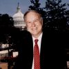 white man in suit and tie with backdrop of state capitol