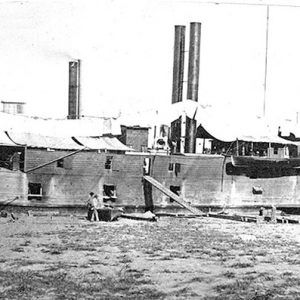 Naval steamboat with smokestacks parked at shore