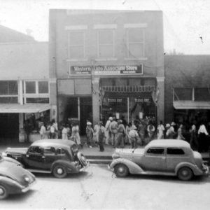 Exterior brick "Western Auto Associate Store" and other buildings with pedestrians, cars