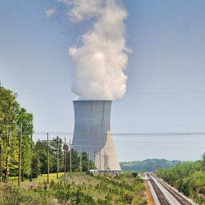 steaming power plant with electrical lines and railroad running parallel toward it