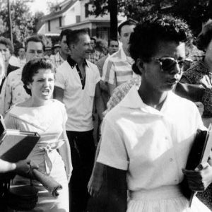 African American woman walks surrounded by hostile white men and women