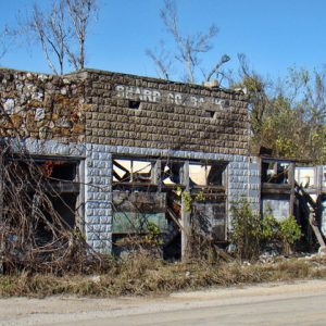 Overgrown abandoned brick and stone building on rural road