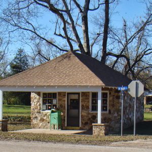 Small single-story stone building with covered entrance on street