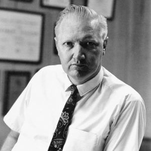 White man with slicked back hair in shirt and tie