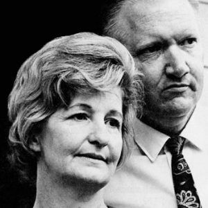 White man in shirt and tie with white woman standing by him