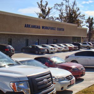 Parked cars outside single-story building with "Arkansas Workforce Center" in blue letters above the entrance