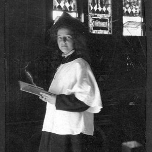 Young white woman wearing religious robes in church with book