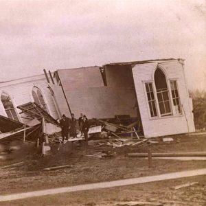 Remaining walls of church building lacking room and people standing amid ruins