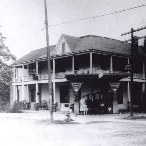 People standing in front of two story white building with balcony