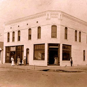 White two story building with people and a car