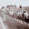 Armed men guarding prisoners working in ditch