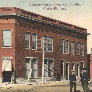 Multistory red brick building with three men in suits standing outside