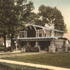 Two story house surrounded by trees and other houses