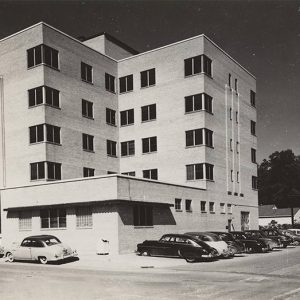 Multistory block-structured building with cars parked in the street alongside it