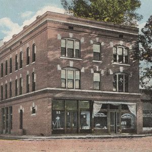 Multistory red brick building with trees and a person standing off to the side