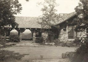 Single-story stone building with porch and trees