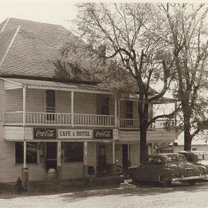 Two story white building with balcony and sign saying "Melbourne Hotel Cafe"