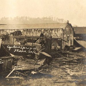 One barn-like structure heavily damaged amid others that are entirely collapsed