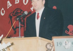 White man speaking into microphone at lectern
