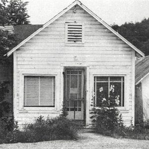 Wooden white building with front door and front facing windows