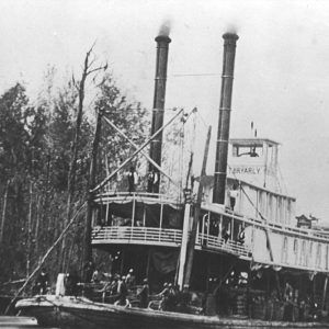 Steamboat steaming down the river with people lined up along the deck