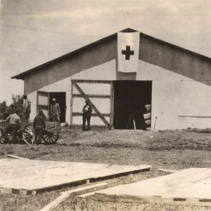 Men standing around barn-like building with large cross on it