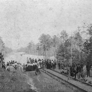 Large group of people standing on railroad tracks looking at flood waters