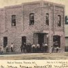 Multistory red brick building with group of people standing on sidewalk adjacent