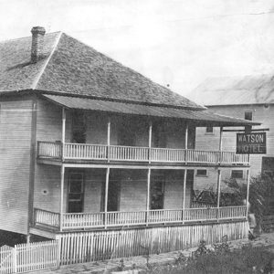 Two story wooden building with covered porch and balcony