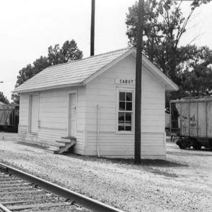 Single story wooden building beside railroad tracks