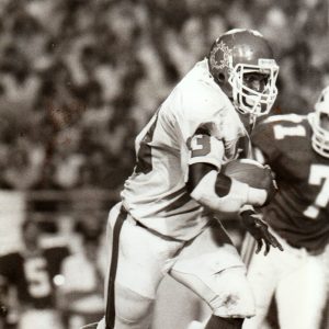 African American man in football uniform running with a football during a game