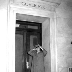 White man standing in marble doorway with "governor" engraved above