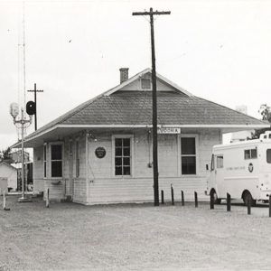 Single story wooden building beside railroad tracks