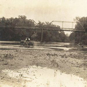 Horse-drawn wagon beneath bridge.