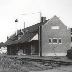 Multi-story brick building beside railroad tracks