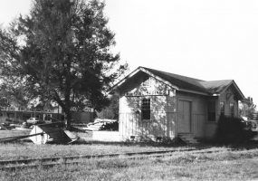 Single story wooden building beside railroad tracks