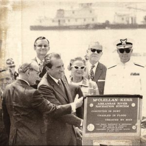 Group of white people standing by plaque saying "Conceived in dust