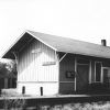 Single story wooden building beside railroad tracks