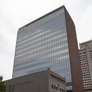 Multistory tower building with brick exterior on one side and glass windows on the other and smaller building next to it