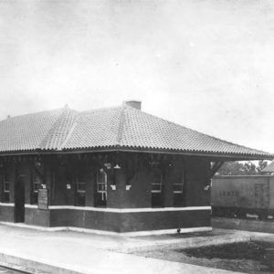 Single story brick building beside railroad tracks with train alongside