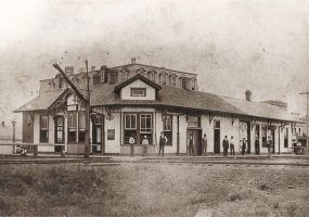 Single story wooden building beside railroad tracks