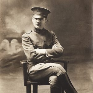 White man in military uniform sitting in chair with legs crossed