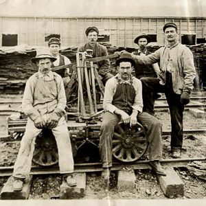 White men seated on hand cart on railroad tracks